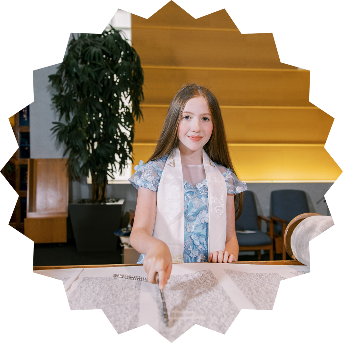 Rebecca at the reading table, following the open Torah scroll with a yad.