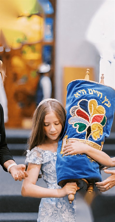 Rebecca carrying a Torah scroll in its embroidered blue mantle.